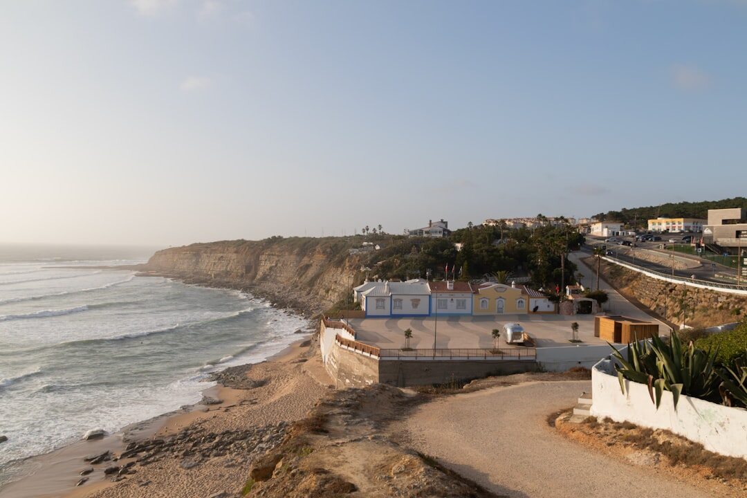 Aerial view of a rugged Atlantic coastline with turquoise water and a modern villa at golden hour